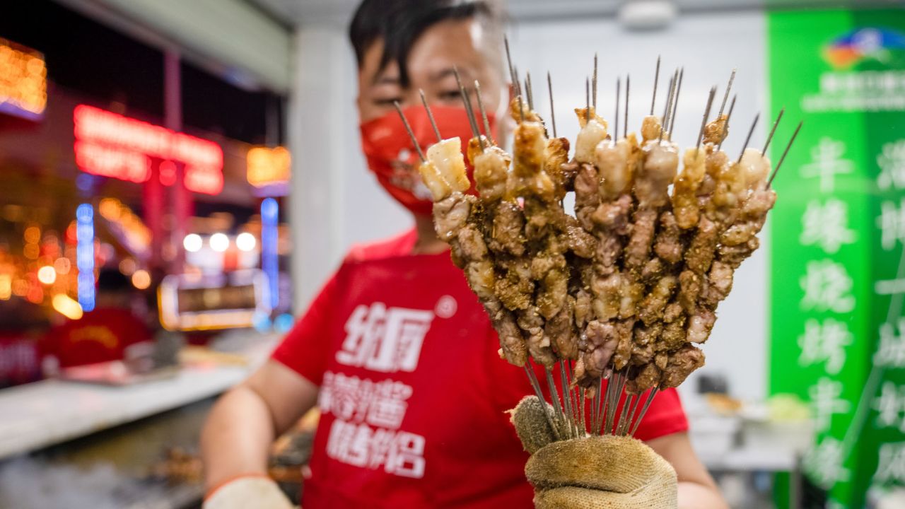 A shop owner shows off grilled meat during a barbecue festival on April 29, 2023 in Zibo, eastern China. The city Zibo became a tourism hot spot after videos of its barbecue went viral online.
